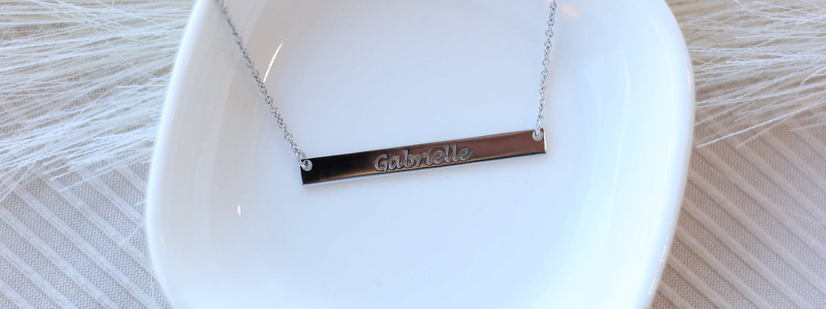 An engraved bar necklace in a ring dish