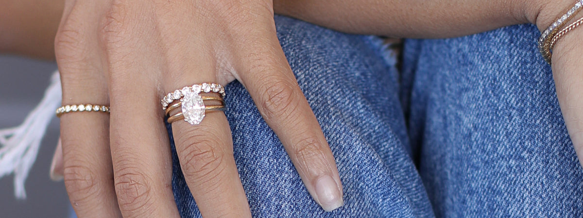 Oval engagement ring and bands on a hand