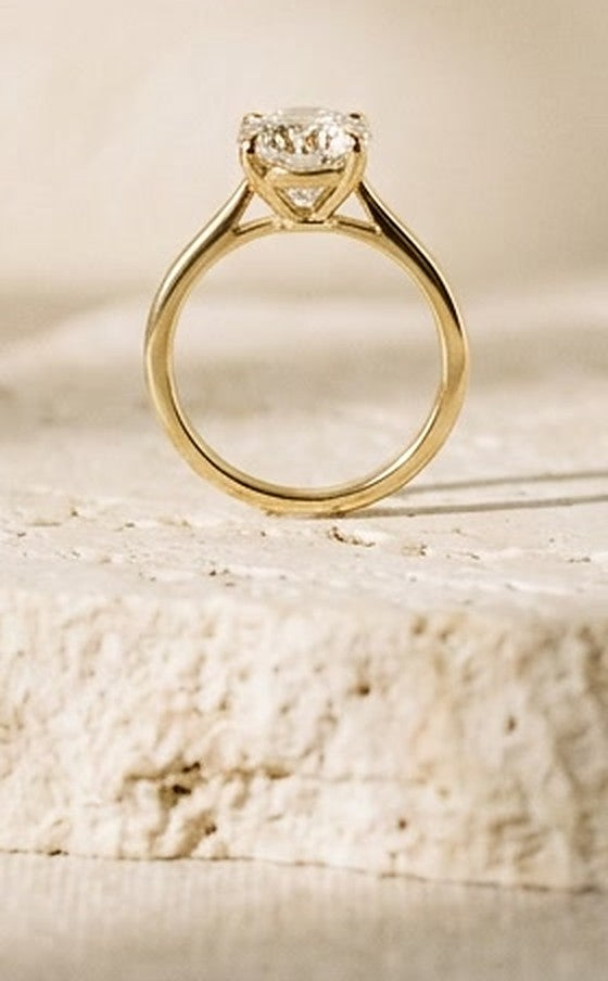 Gold solitaire engagement ring on a stone block