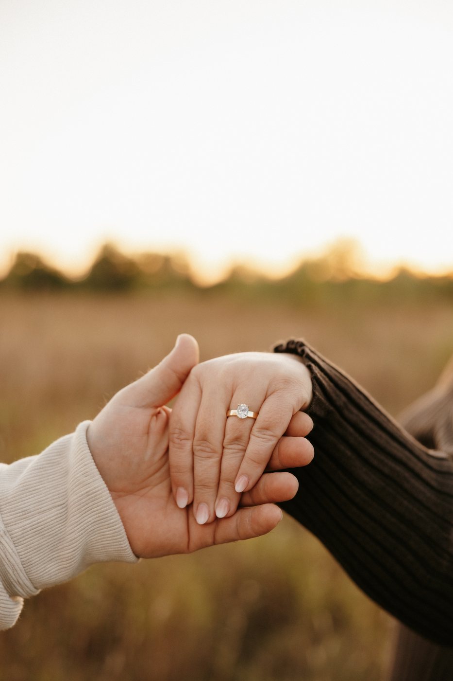 A newly engaged couple holding hands, showing her Alloy engagement ring