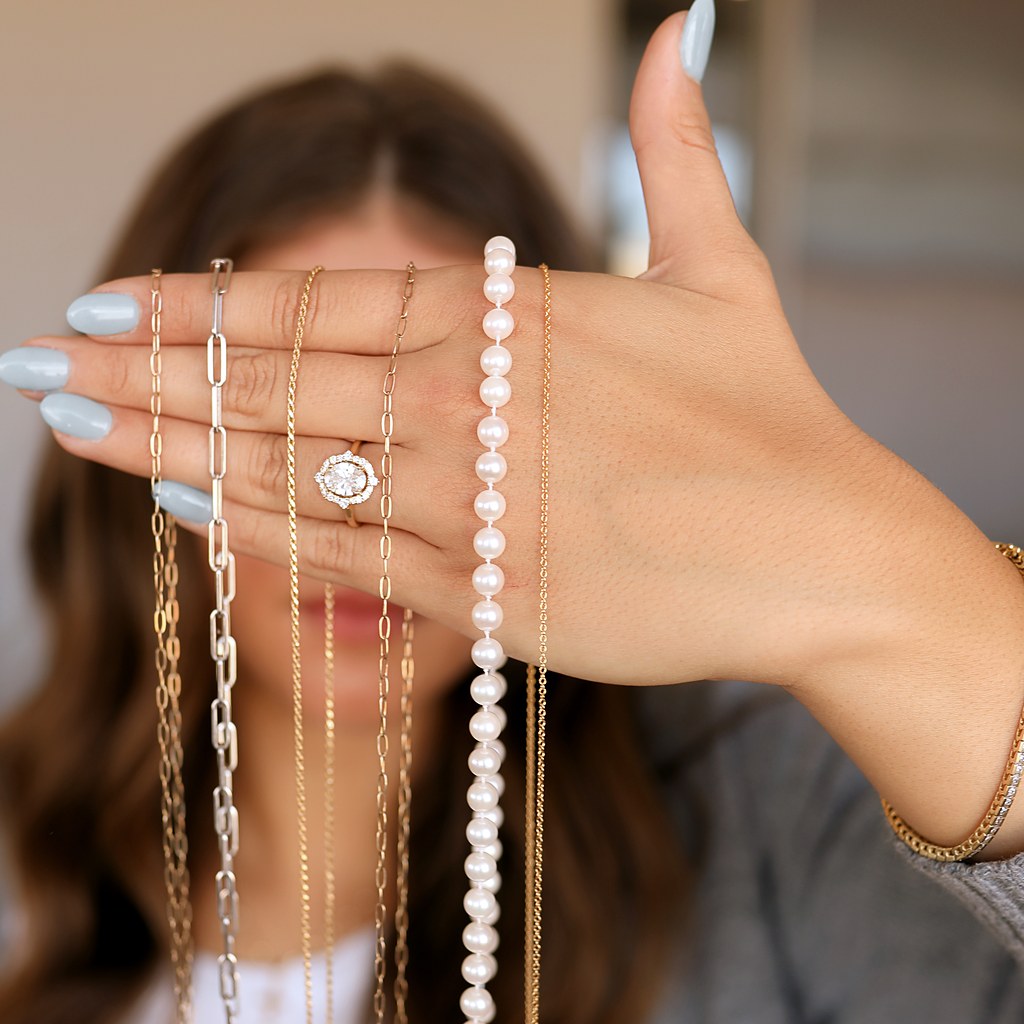 Chains and a pearl necklace held in hand